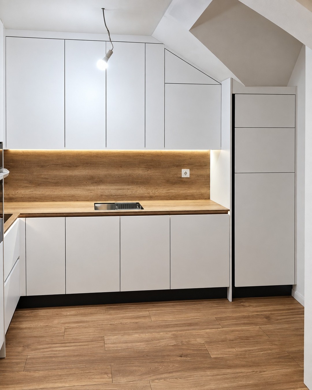 Made-to-measure white kitchen fitted below a sloped ceiling